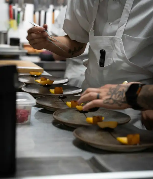 Un chef sirviendo platillos en la cocina de un restaurante